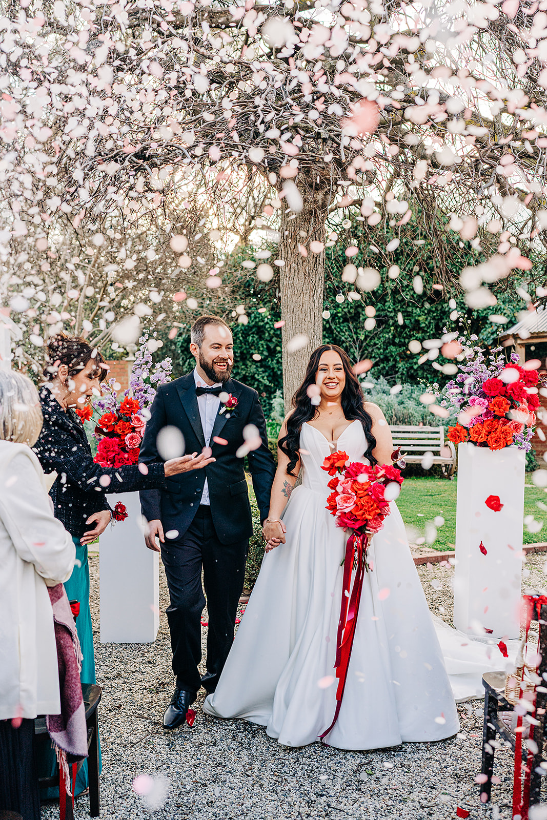couple exiting ceremony with big smiles while confetti is being thrown over them