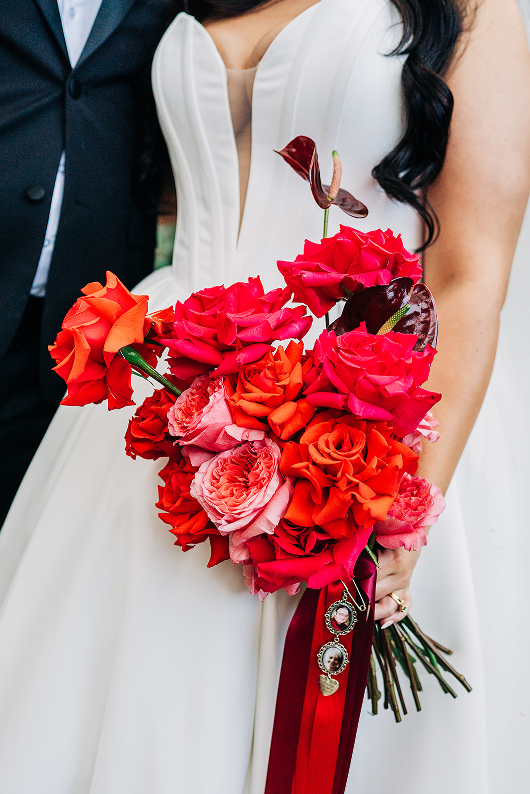 close up of red and pink bouquet with broach and photos of grandparents sitting below bouquet