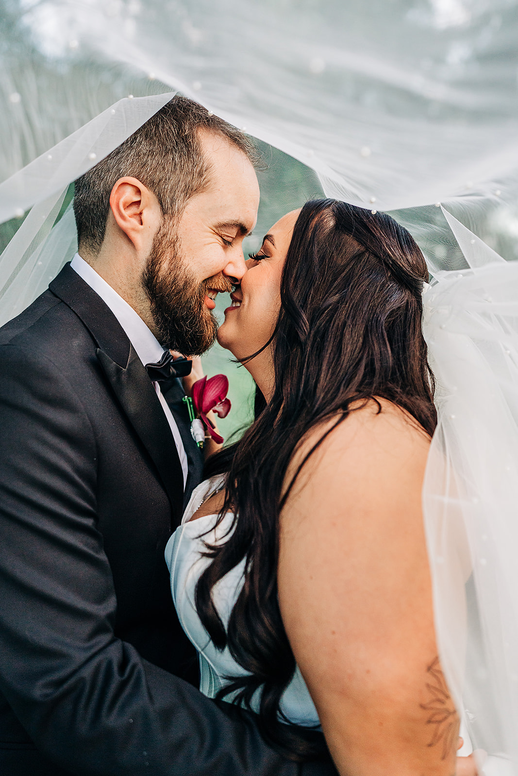 couple under veil nearly kissing