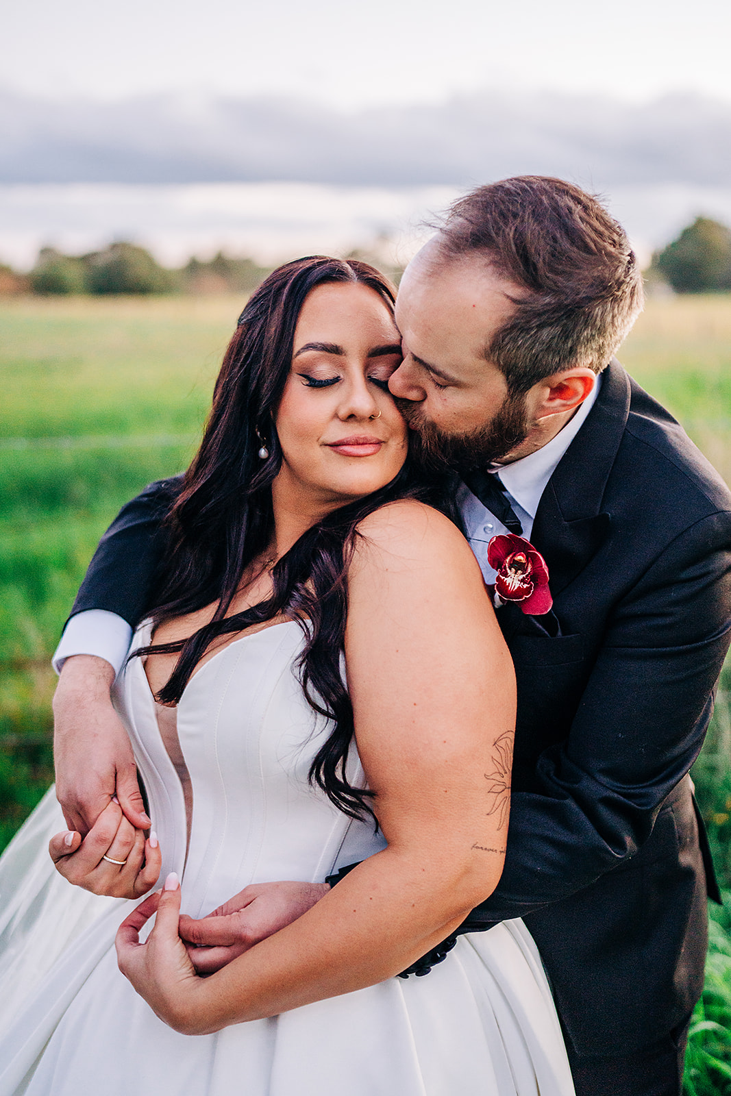 couple cuddle during wedding photos. groom kisses cheek.