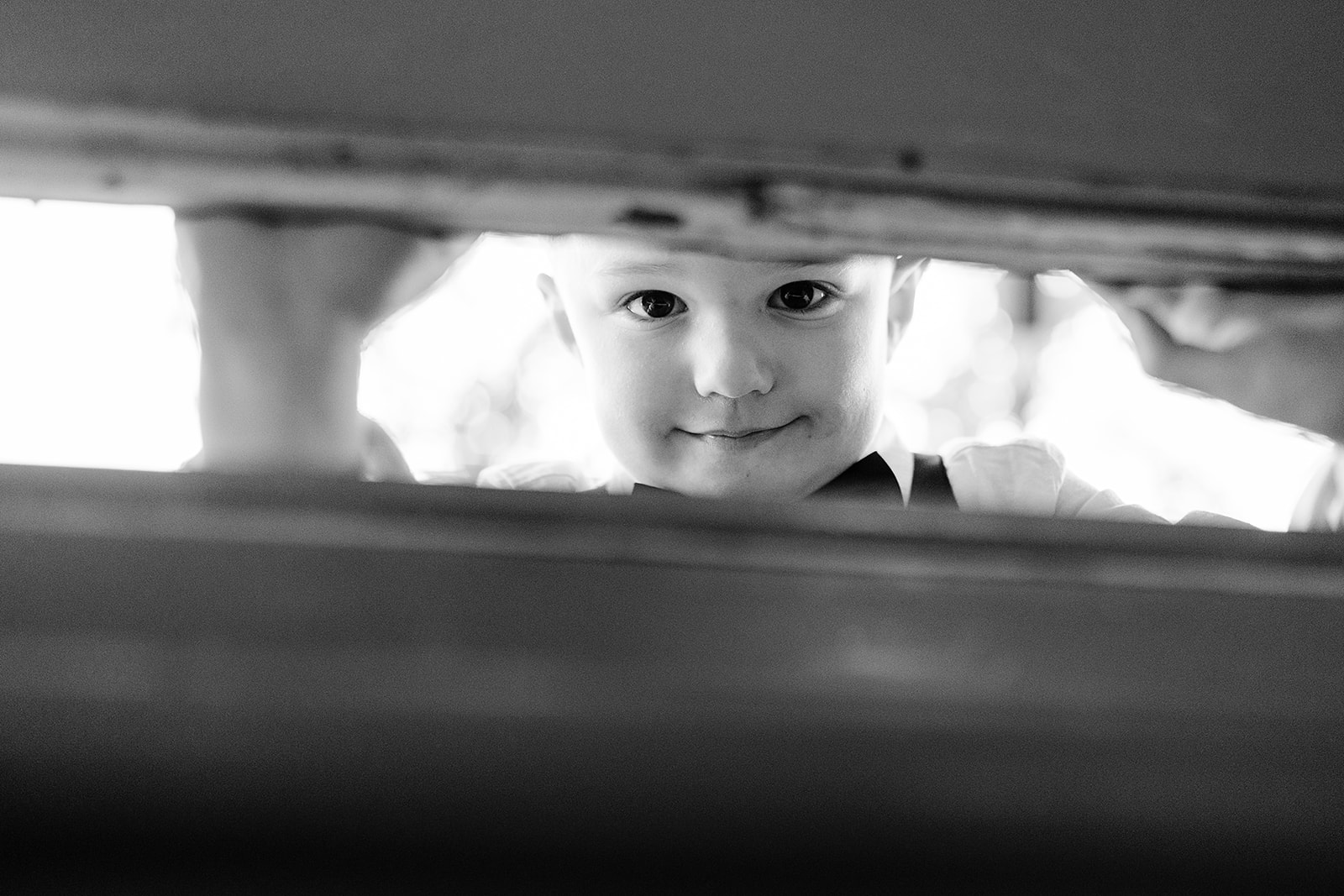 child peering through gap in window