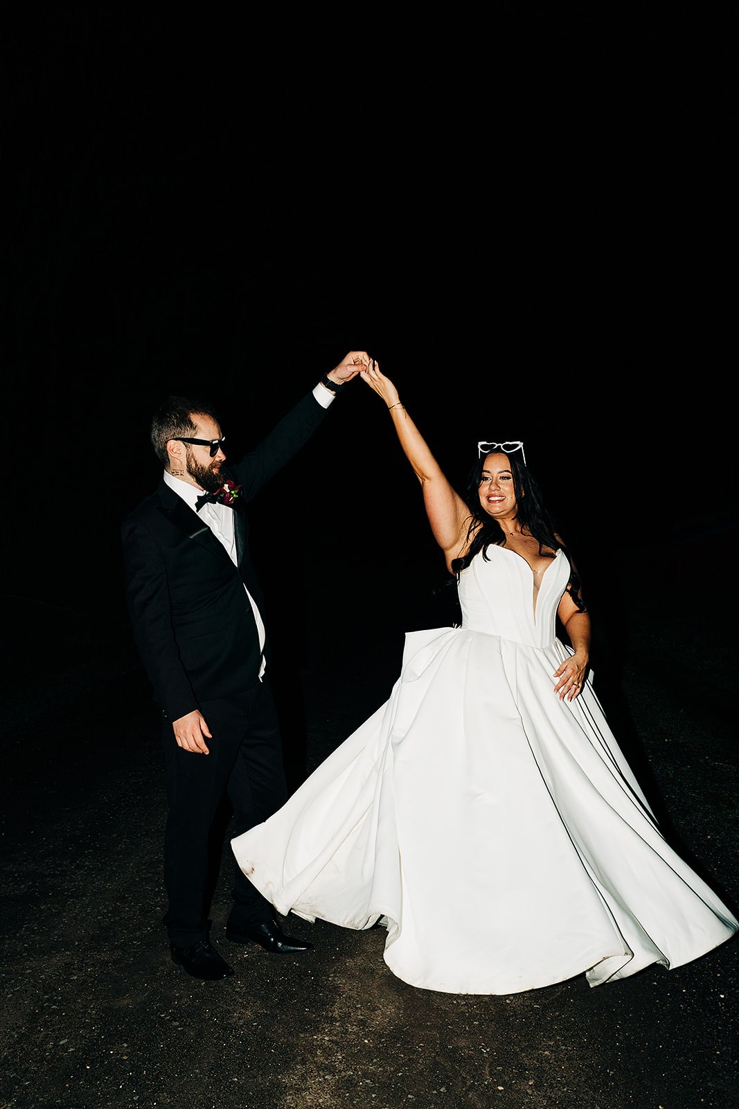 couple doing a spin during their wedding night photos at harvest home