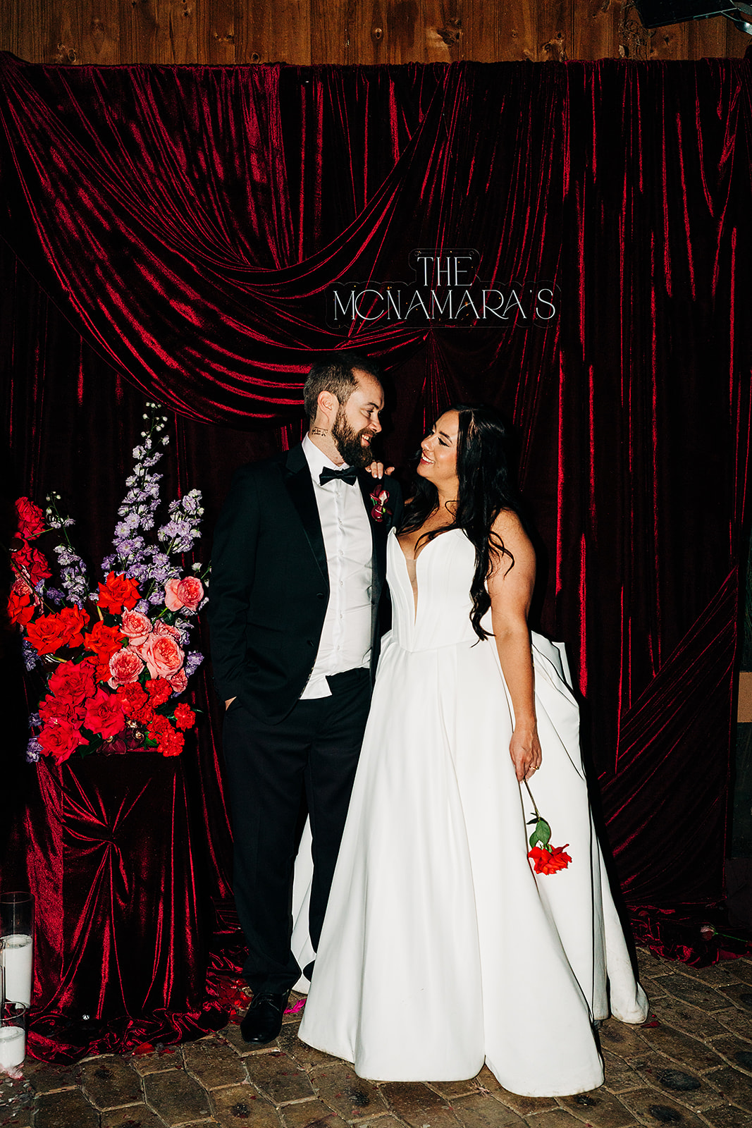 couple in front of red wedding backdrop draping